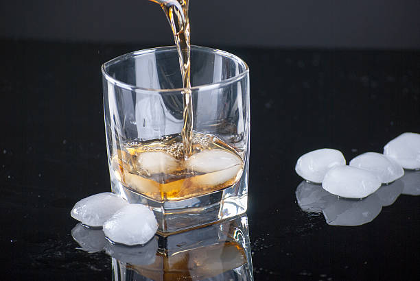 istock Pouring Whiskey Glass - Scotch Glass with ice cubes 513598380