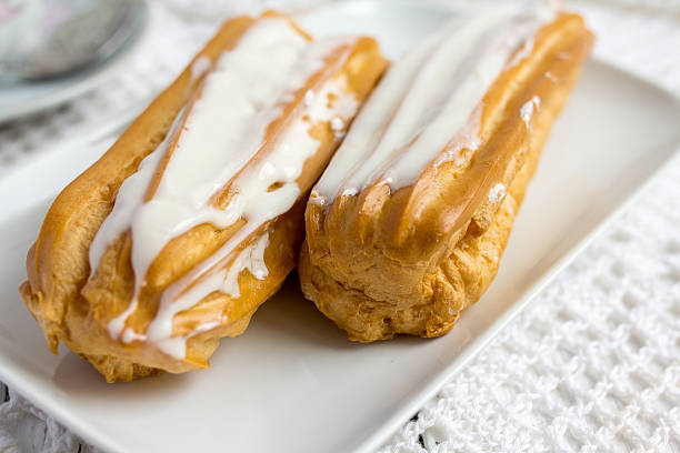 Dessert Eclair with whipped cream Dessert Eclair with whipped cream and sugar icing on a white table tea party horizontal nobody indoors stock pictures, royalty-free photos & images