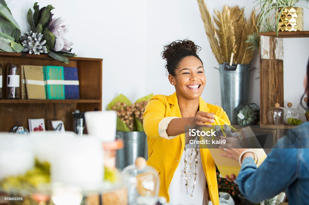 Saleswoman helping customer Saleswoman (16-17 years, mixed race African American) helping customer. Small Business Stock Photo