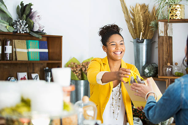 Saleswoman helping customer Saleswoman (16-17 years, mixed race African American) helping customer. merchandise stock pictures, royalty-free photos & images