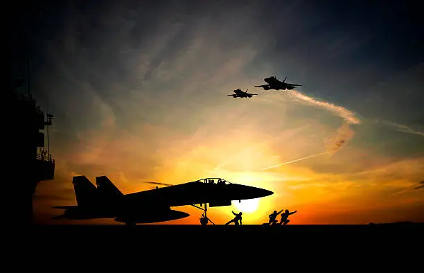 Military aircraft before take-off from aircraft carrier on sunset background