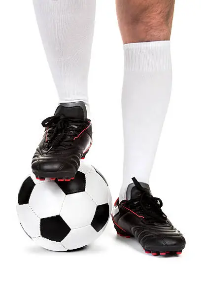 Legs of soccer player with ball on white background