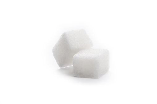 White sugar cubes and a teaspoon on blue background