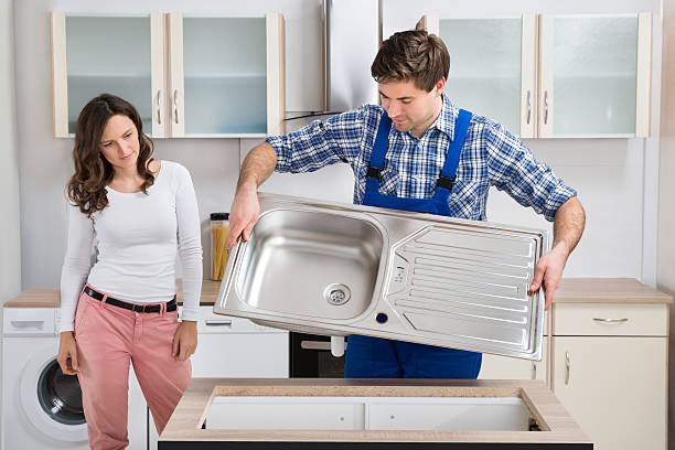 Woman Looking At Worker Carrying Kitchen Sink