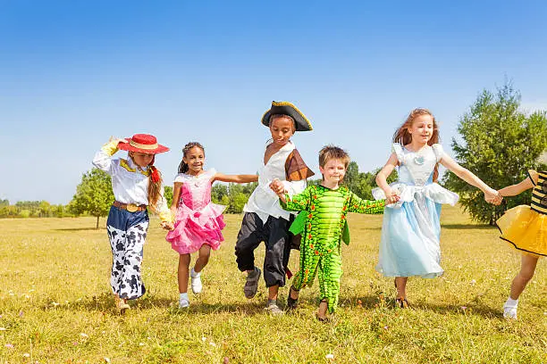Photo of Running kids wearing costumes outside in field