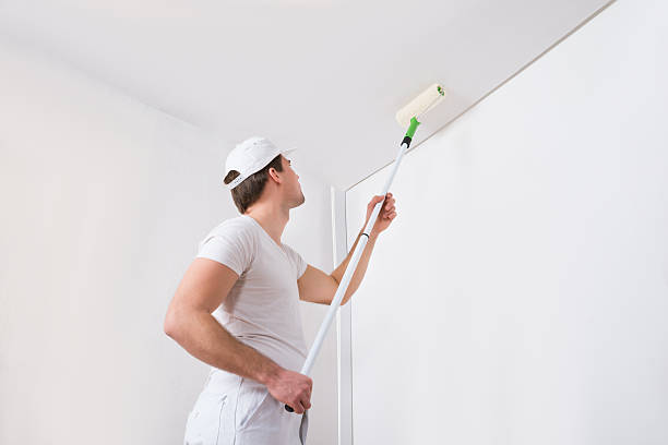 Painter Painting On Wall Young Painter In White Uniform Painting With Paint Roller On Wall ceiling stock pictures, royalty-free photos & images