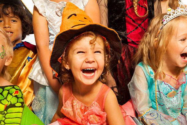 Laughing girl in Halloween costume with friends Little laughing girl wearing dress and Halloween hat surrounded by friends kids, close-up studio portrait carnival children stock pictures, royalty-free photos & images