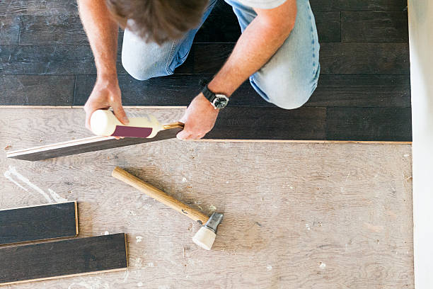 Man installing hardwood floor during home renovations.