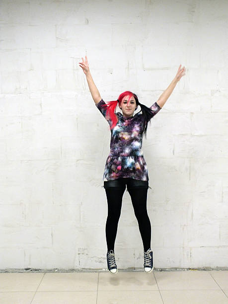 istock Cheerful girl jumping against a white wall 513625536