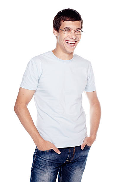 Laughing guy with hands in pockets Young hispanic man wearing glasses, blue jeans and t-shirt, standing with hands in pockets and laughing - laughter concept nerd teenager stock pictures, royalty-free photos & images