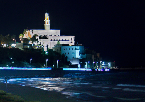 The famous Al-Barh mosque tower in Jaffa, Tel Aviv, Israel at night reflecting in the Mediterranean Sea