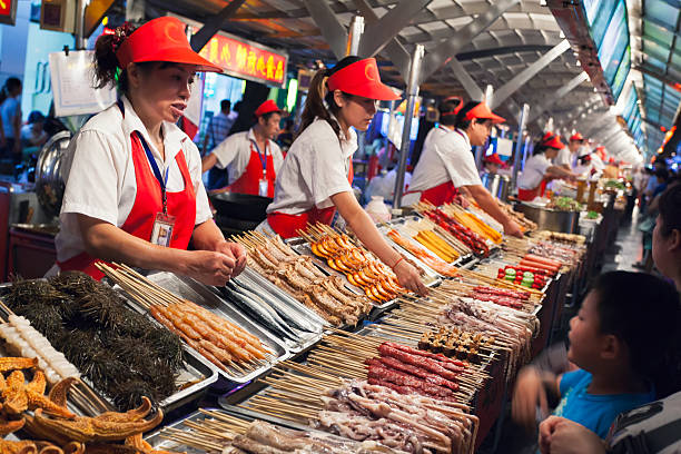 Wangfujing snack street Beijing, China - August 26, 2014: Market vendors at Wangfujing snack street offer their customers a very wide variety of foods from their street food stalls. wangfujing stock pictures, royalty-free photos & images