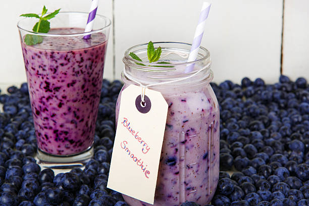 czarna jagoda smoothie w szklanych ze słomką - blueberry smoothie glass striped zdjęcia i obrazy z banku zdjęć