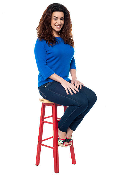 istock Long curly haired lady seated on red stool 513635477