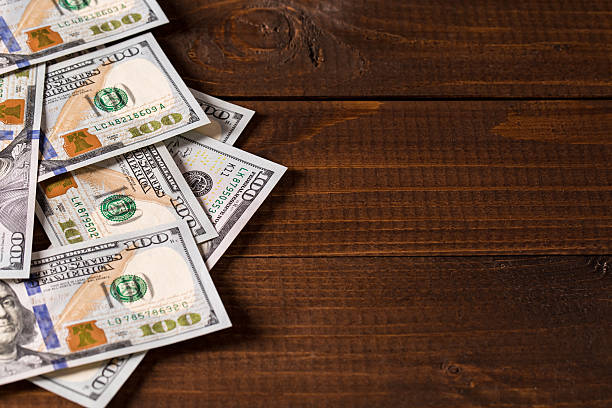 istock new 100 US dollars bills on wooden background 513636460