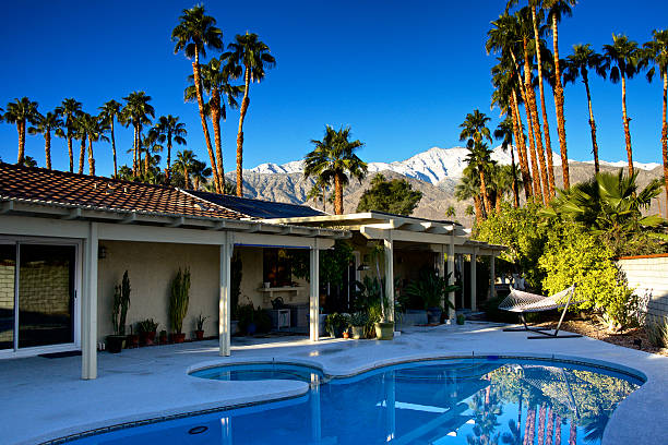 Backyard pool, Palm Springs home in Winter, Southern California, USA A Mid-20th Century home with a backyard pool and patio area is seen in winter season, Palm Springs, Coachella Valley, Riverside County, Southern California, Western USA. California Fan Palm Trees and the snow covered San Jacinto Mountains are viewed in morning light.  fan palm tree photos stock pictures, royalty-free photos & images