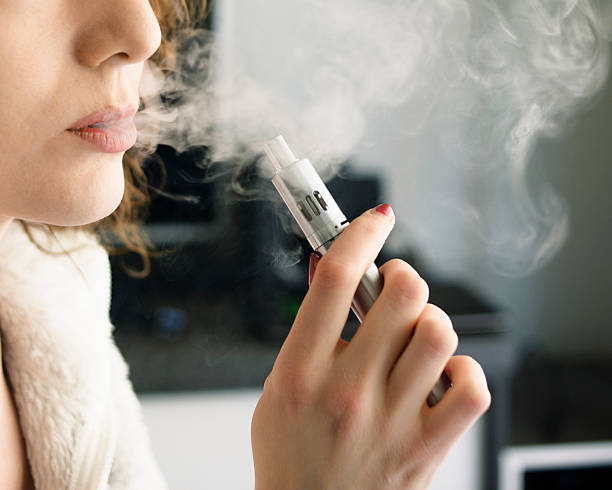 woman smoking an e-cigarette - vape stockfoto's en -beelden
