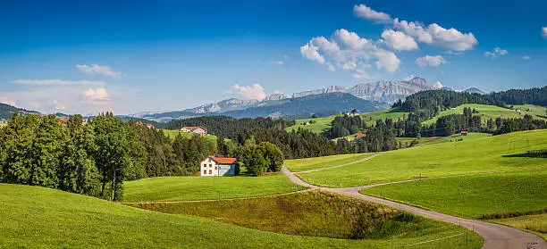 Beautiful view of idyllic mountain scenery in the Alps with green meadows and famous Saentis summit in the background on a sunny day with blue sky and clouds in summer, Appenzellerland, Switzerland