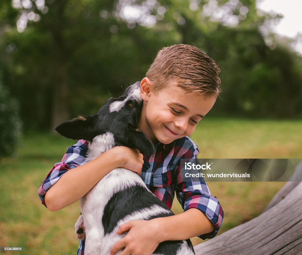 Closeup cute rascal boy gives his puppy a big hug Closeup of cute rascal boy who gives his puppy a big hug. The child and his best animal friend sitting on a log in nature Dog Stock Photo