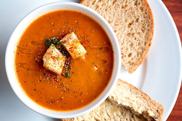 Tomato soup and croutons A bowl of fresh tomato soup in white ceramic bowl, garnished with herbs, croutons, seasoning and a drizzle of olive oil, and served with crusty wholemeal bread. soup stock pictures, royalty-free photos & images