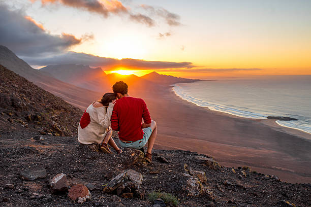 couple enjoying beautiful sunset on fuerteventura island - canarische eilanden stockfoto's en -beelden