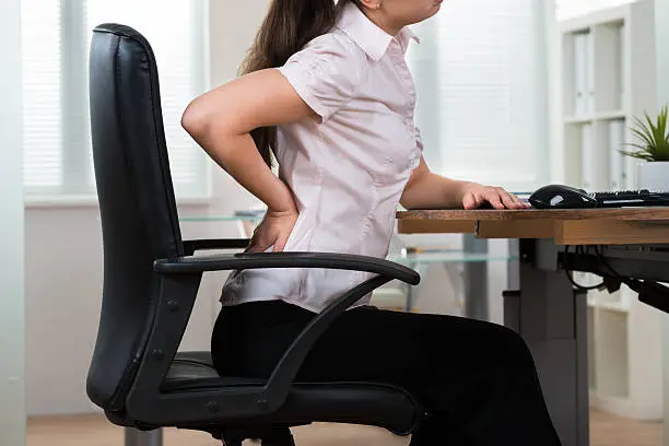 Close-up Of Young Businesswoman On Chair Having Backpain In Office