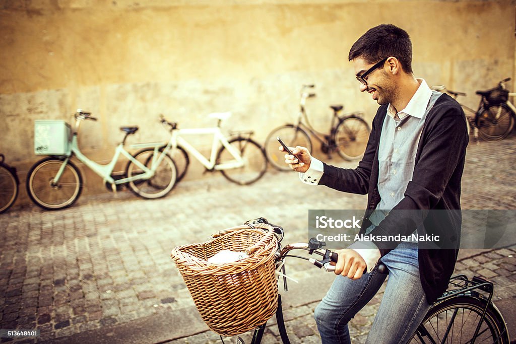 Using a smart phone on the bicycle Young man enjoying bicycle riding in the city while using his mobile phone 20-29 Years Stock Photo