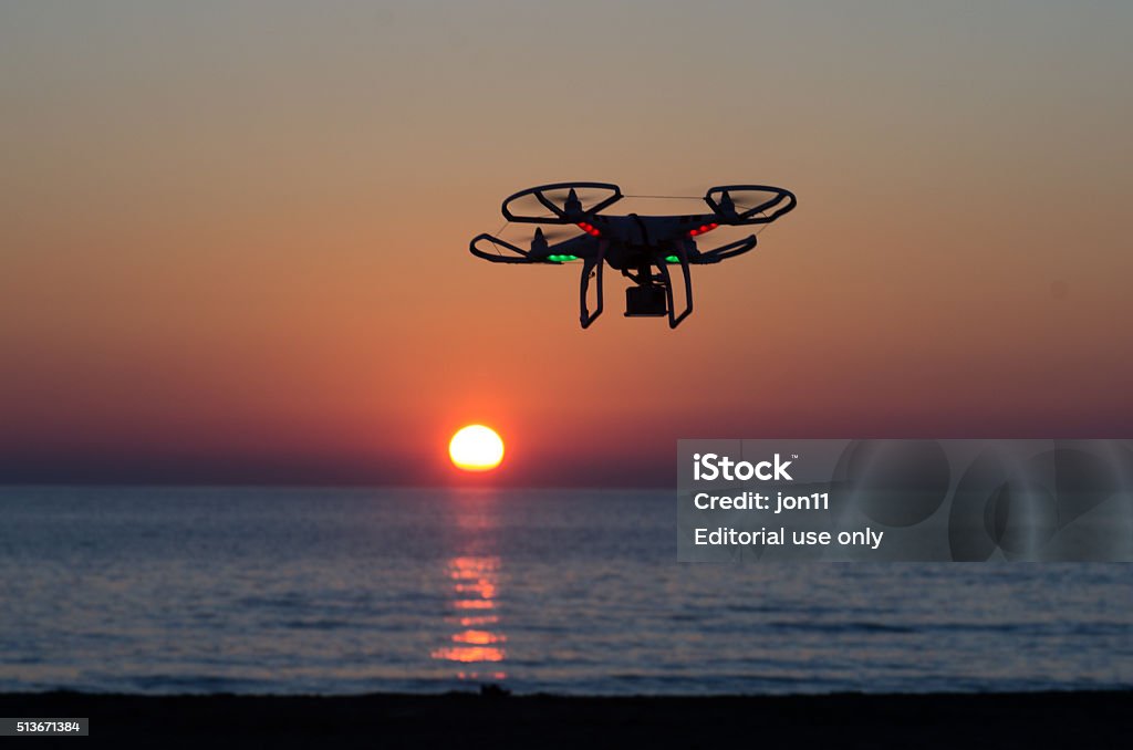 Flying drone with camera on the sky at sunset Viareggio, Italy - October 30, 2014: quadcopter flies with camera at sunset Quadcopter industry is told to be growing at triple digitsevery year, for a market expected to pass the 20 billion in the 2020. The dji is a chinese company leader of quadcopter industry, and the phantom is expected to be the top seller gift for christmas 2015 Aerial View Stock Photo