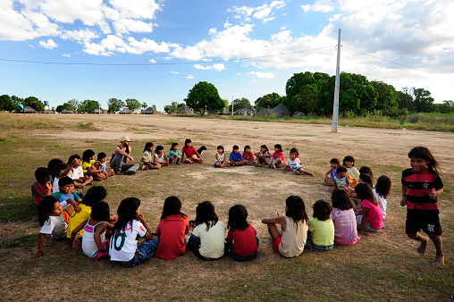 Nova Xavantina, Brazil - June 16, Children of Xavante indigenous people with their teacher in an outdoor class in his village