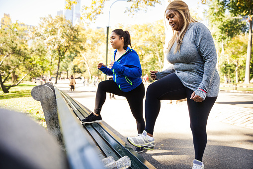 Two plus size women exercising in Central Park, New York during a beautiful day.
