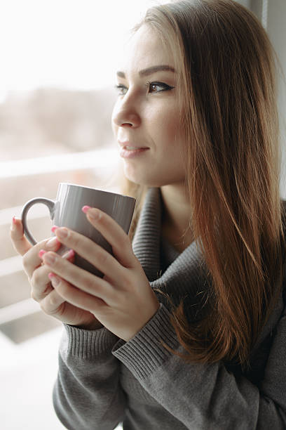 istock Attractive young woman sitting with coffee at window 513678732