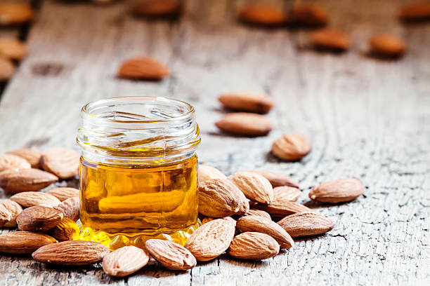 Sweet Almond Oil, first extraction, in a small glass jar Sweet Almond Oil, first extraction, in a small glass jar, dry almond nuts on an old wooden background, selective focus almond stock pictures, royalty-free photos & images