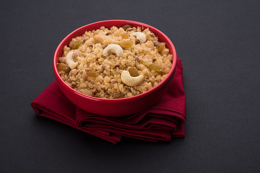 indian gujrati or maharahashtrian or south indian sweet dish lapsi broken wheat sweet pudding payasam pongal or daliya sheera, famous sweet food in india, also known as halwa, served in a ceramic bowl