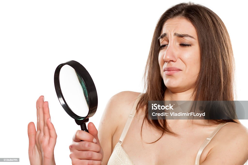 manicure disgusted young woman analyzing her nails with a magnifying glass Fear Stock Photo