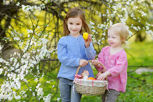 deux petites filles tenant un panier de œufs de pâques - figurine easter egg easter holiday photos et images de collection