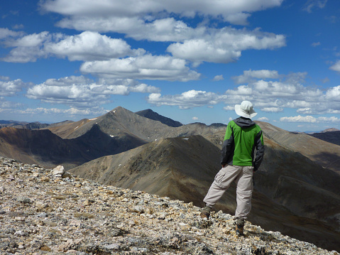 A hiker on the 13,794 foot on Square Top Mountain looks towards the Argentine Pass and the Continental Divide with Grays and Torreys Peaks standing tall on the horizon in the distance.