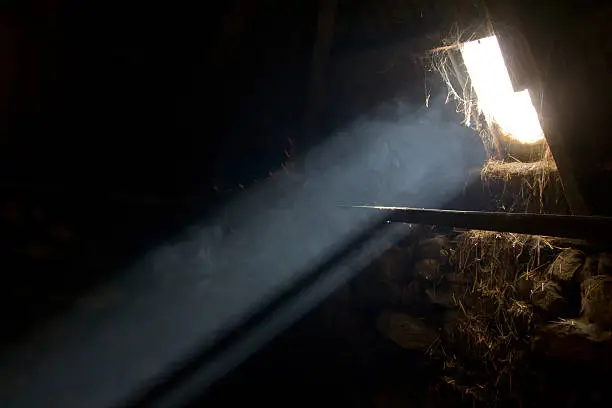 A bright light beam enters an old hay barn