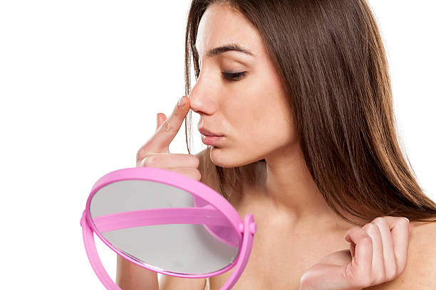 Rhinoplasty worried young woman lifting her nose in front of a mirror human nose stock pictures, royalty-free photos & images