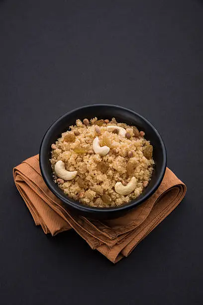 indian gujrati or maharahashtrian or south indian sweet dish lapsi broken wheat sweet pudding payasam pongal or daliya sheera, famous sweet food in india, also known as halwa, served in a ceramic bowl