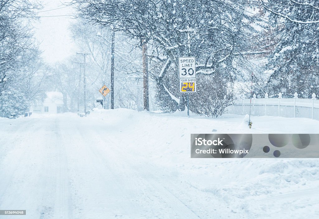 Digital Radar Speed Warning Road Sign in Winter Snow Blizzard A suburban Rochester, New York State road "SPEED LIMIT 30" traffic road sign with an automated radar gun digital display flashing the car's actual speed - 24 miles per hour - during an extremely heavy February whiteout winter blizzard snow storm. Radar Stock Photo