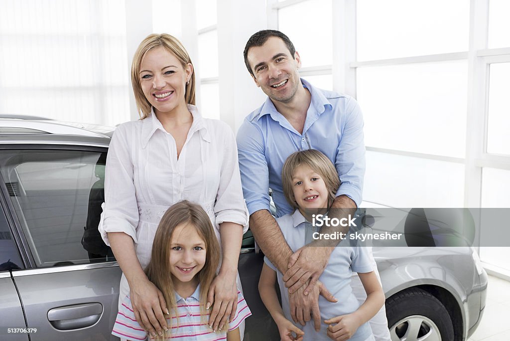 Family in a showroom. Parents with their children in a car showroom looking at the camera.    Car Stock Photo