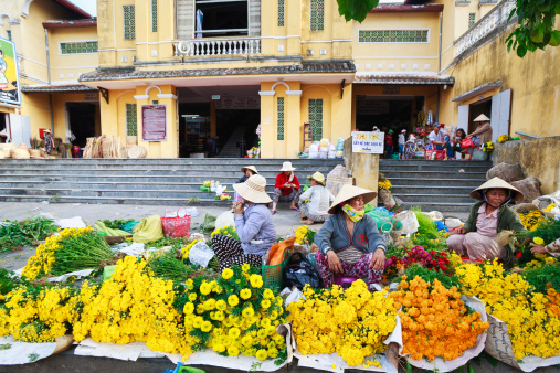 Hoi An, Vietnam - May 12, 2014: Unidentified flower vendors at the Hoi An market in Hoi An Ancient Town, Quang Nam, Vietnam. Hoi An is recognized as a World Heritage Site by Unesco.