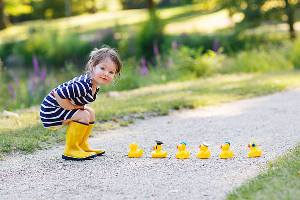 niña encantadores de dos jugando con goma amarilla ducks - frog batrachian animal head grass fotografías e imágenes de stock