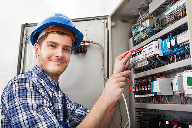 Technician Examining Fusebox With Multimeter Probe Side view of male technician examining fusebox with multimeter probe electrician multimeter stock pictures, royalty-free photos & images