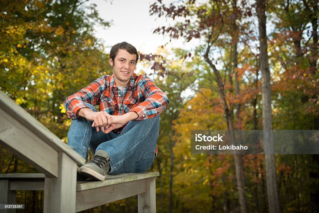 Lächelnde junge sitzt auf der Vorderseite von Bäumen mit Herbst Blätter - Lizenzfrei Blatt - Pflanzenbestandteile Stock-Foto