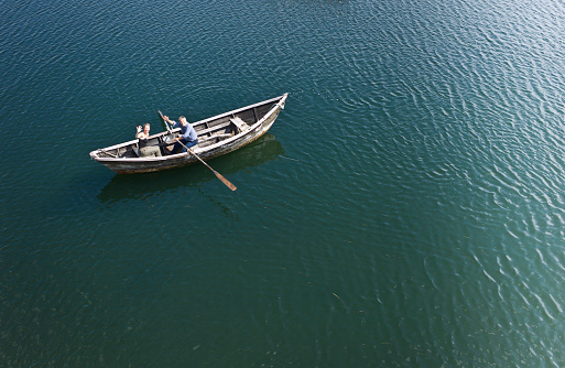 Aerial view of a man rowing a dory on the sea with a woman aboard.