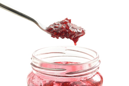 Homemade strawberry jam scooped out of a jam jar.