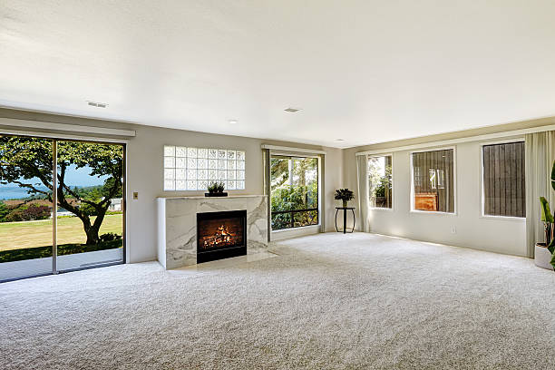 Beautitful living room with fireplace and walkout deck Bright empty room with fireplace and carpet floor. Glass slide door to backyard carpet stock pictures, royalty-free photos & images
