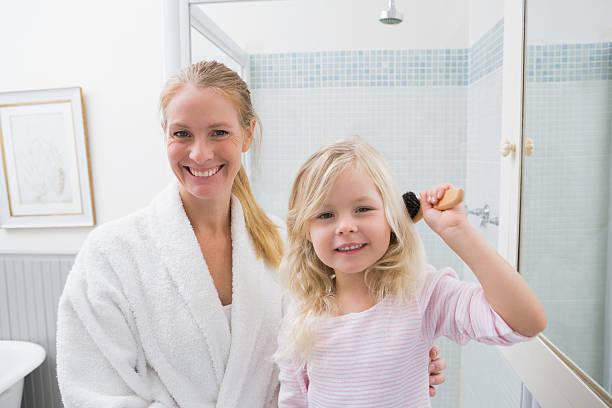 istock Happy mother and daughter brushing hair 513732001