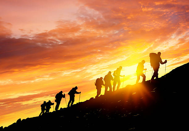 Silhouettes of hikers At Sunset Silhouettes of hikers climbing the mountain at sunset group of people people recreational pursuit climbing stock pictures, royalty-free photos & images